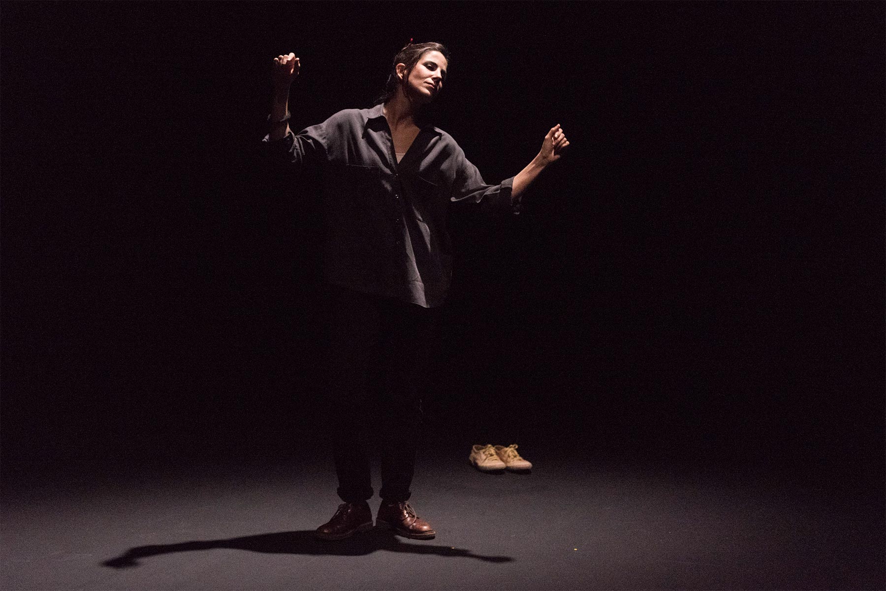 Fotografía artística de una mujer con ropa casual en un escenario oscuro, resaltando la expresión y postura para promover ideas de creatividad y autoconocimiento.