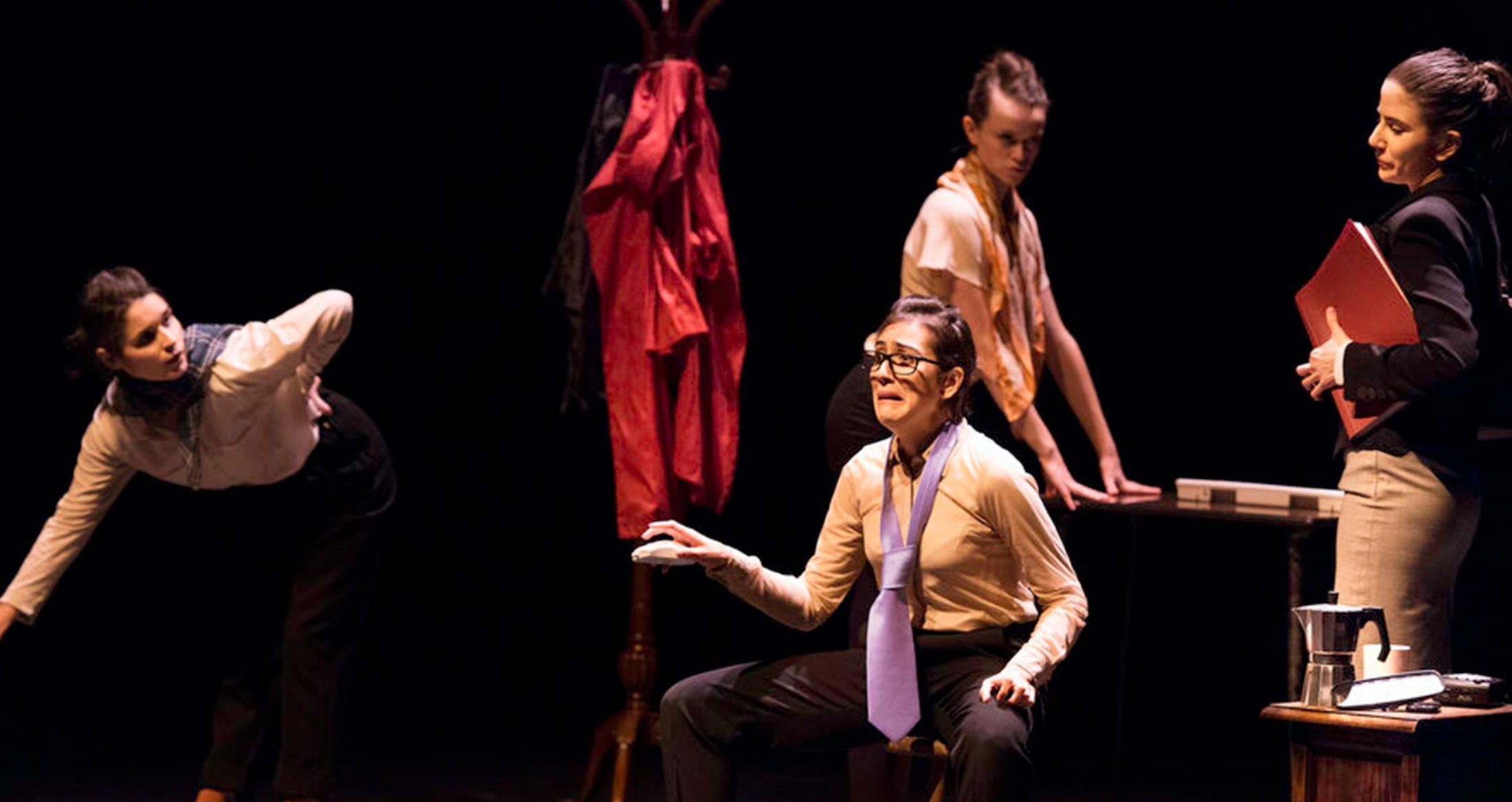 Profesional de teatro actuando en escena, representación teatral con diálogo emotivo, iluminación dramática y vestuario formal para potenciar la expresividad en un entorno artístico.