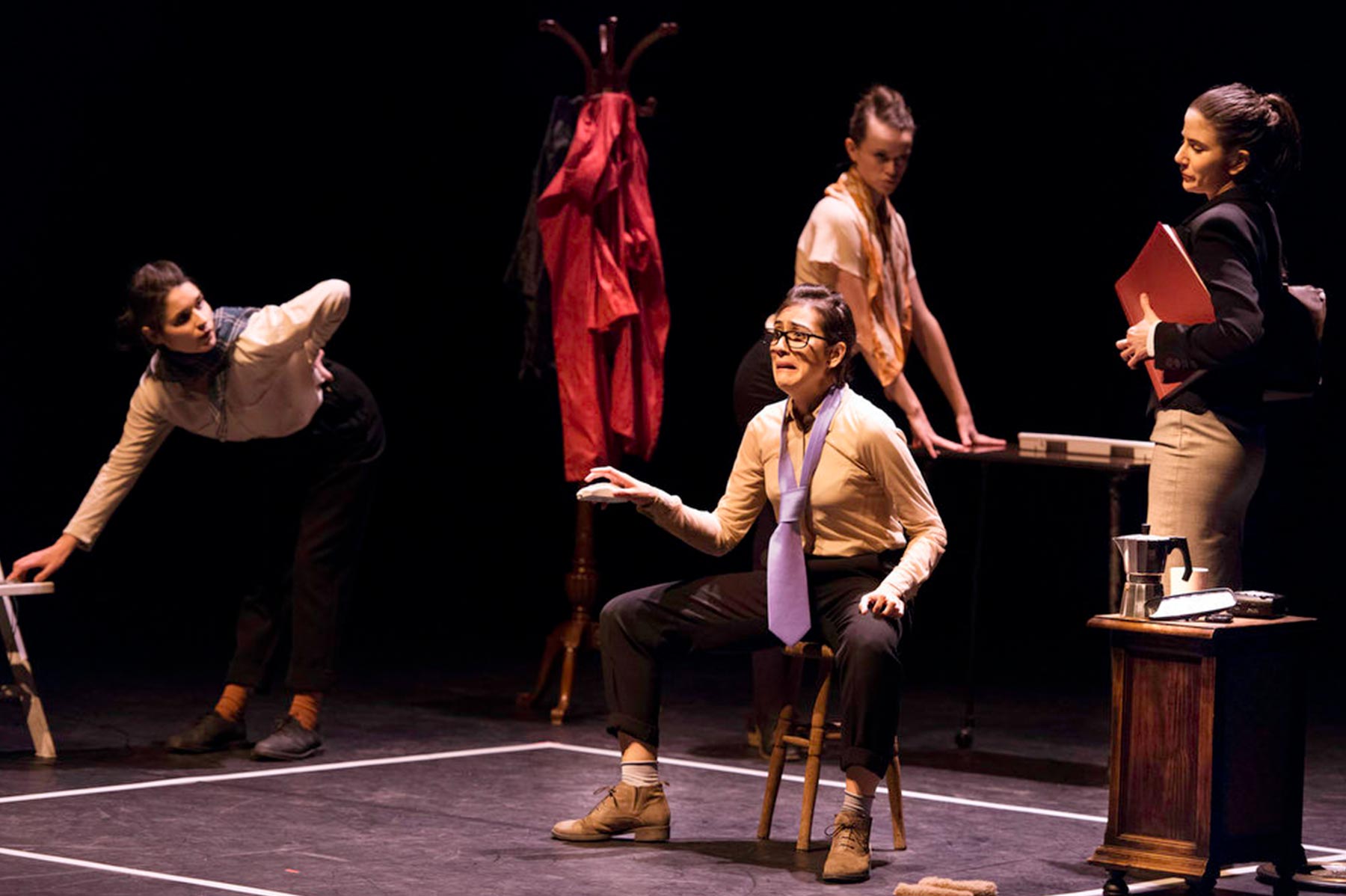 Maestra en teatro en escena con talento y pasión, actuando con un grupo de mujeres en una obra teatral en un escenario oscuro, transmitiendo emociones intensas y expresión artística.