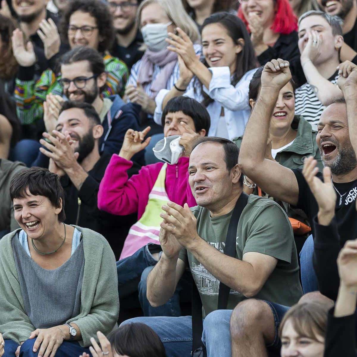 Sonriente grupo de personas disfrutando en un evento al aire libre, cultura, diversidad, felicidad, comunidad, alegría, convivencia, sonrisa, interacción social, ocio, entretenimiento, participación, amistad, celebración, espontaneidad, expresión, emociones, diversión, unión, grupo alegre en un contexto social, libertad, felicidad compartida.