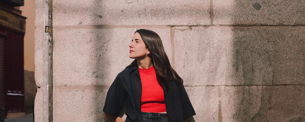 Moderna mujer en calle urbana posando en pared de piedra, estilo casual con ropa moderna y elegante, fotografía de moda y lifestyle, moda urbana, look casual, tendencias en ropa, Andrea Jiménez.